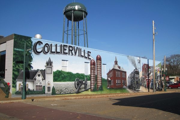 Collierville, TN mural featuring historic landmarks, a steam train, and a water tower, showcasing the town's rich heritage. Professional lawn care services available in Collierville and surrounding Mid-South areas.